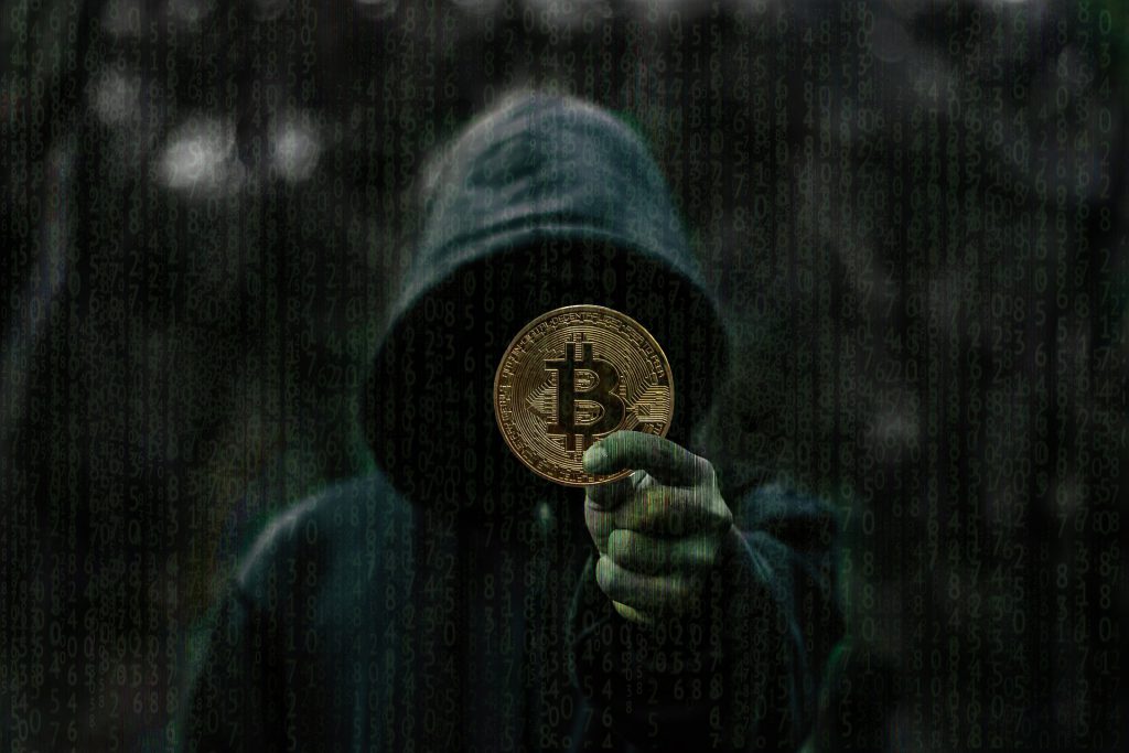hooded person holds bitcoin